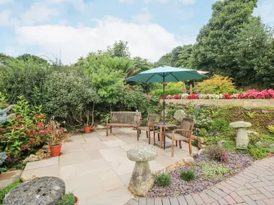 a patio with a table and chairs and an umbrella at The Hideaway in St Austell