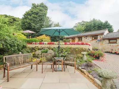 a patio with two benches and a table with an umbrella at The Hideaway in St Austell