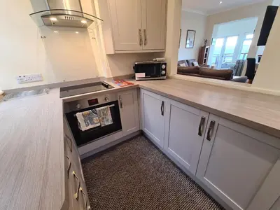 a kitchen with white cabinets and a counter with a microwave at Lower Tresulian in Saint Mawes