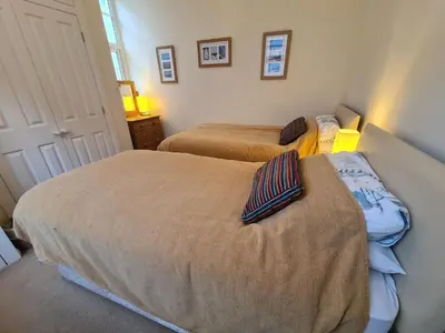 a bedroom with two beds and a door with a window at Lower Tresulian in Saint Mawes