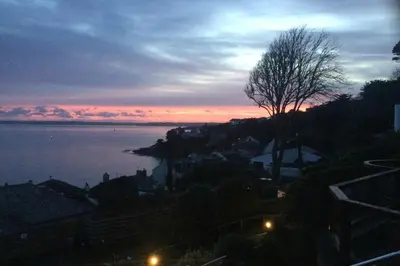 a view of the ocean at sunset with a tree at Lower Tresulian in Saint Mawes