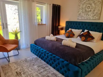 a bedroom with a large bed with a blue headboard at 4 Bed Villa Sleeps 8 -Private Terrace-Free parking in St Austell