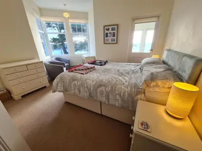 a bedroom with a bed and a chair and windows at Upper Tresulian in Saint Mawes