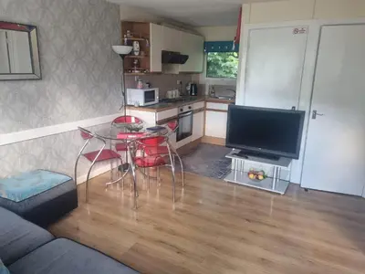 a living room with a table and a tv and a kitchen at Villa Sleeps 4 with Free Parking in Camelford
