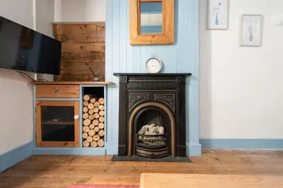 a room with a fireplace with a clock on the wall at Saffron Cottage, St Ives in St Ives