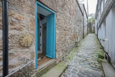 an alley with a blue door on a stone building at Saffron Cottage, St Ives in St Ives