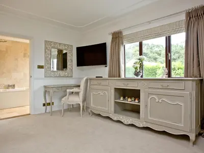 a bathroom with a dresser with a television and a table at Hewas Water House in Grampound