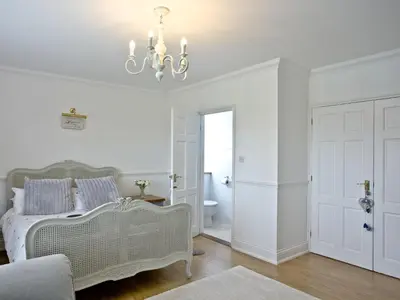 a white bedroom with a bed and a chandelier at Hewas Water House in Grampound