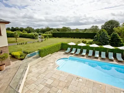 a swimming pool in a garden with chairs and a yard at Hewas Water House in Grampound