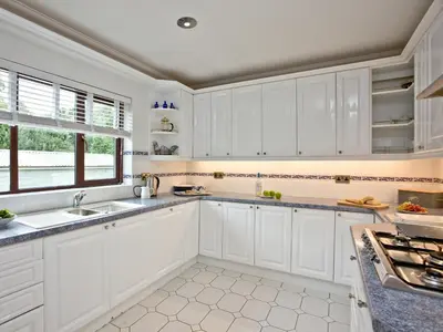 a white kitchen with white cabinets and a window at Hewas Water House in Grampound