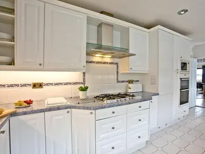a white kitchen with white cabinets and a stove at Hewas Water House in Grampound