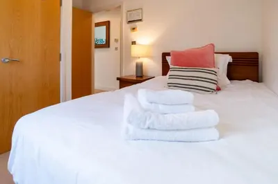 a bed with white towels stacked on top of it at Trewhiddle Retreat V1 by Together Travel - Luxury 4-Bedroom Villa in St Austell