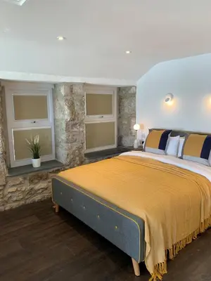 a bedroom with a large bed and two windows at Beach House Apartment 1 - St. Ives harbour front apartment with stunning views in St Ives