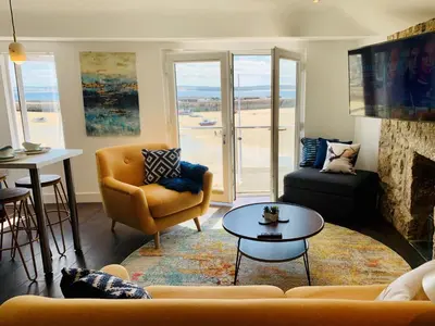 a living room with a couch and a fireplace at Beach House Apartment 1 - St. Ives harbour front apartment with stunning views in St Ives