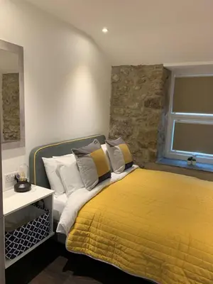 a bedroom with a bed with a yellow blanket at Beach House Apartment 1 - St. Ives harbour front apartment with stunning views in St Ives