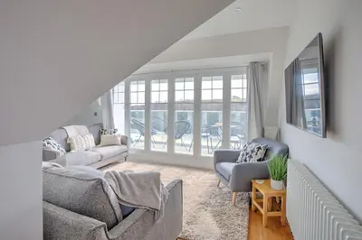 a living room with couches and chairs and windows at The Tower, 5 Corisande Manor in Newquay