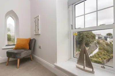 a living room with a chair and a window at The Tower, 5 Corisande Manor in Newquay