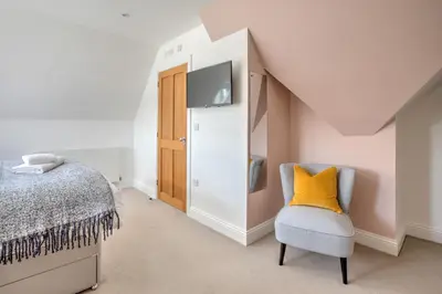 a bedroom with a bed and a yellow pillow on a chair at The Tower, 5 Corisande Manor in Newquay
