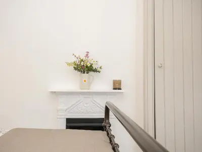 a white table with a vase of flowers on it at Skylarks in Looe