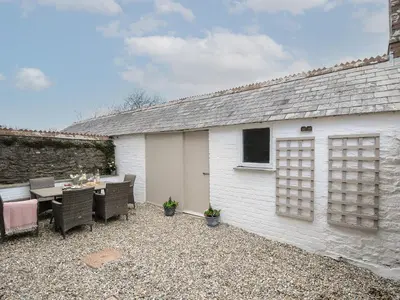 a white shed with a table and chairs in front of it at Skylarks in Looe