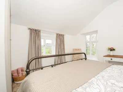 a bedroom with a bed in a room with windows at Skylarks in Looe