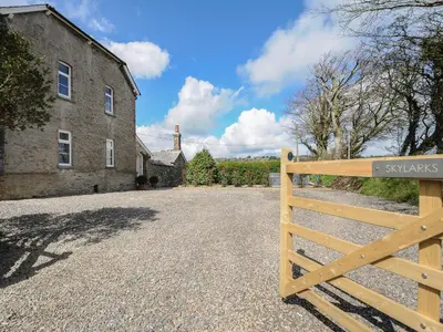 a wooden gate in front of a building with a house at Skylarks in Looe