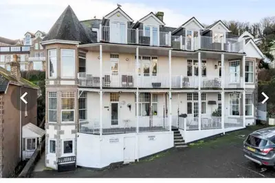 a large white house with a car parked in a parking lot at Little Haven St Ives - with parking in St Ives