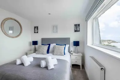a white bedroom with two beds and a window at Little Haven St Ives - with parking in St Ives