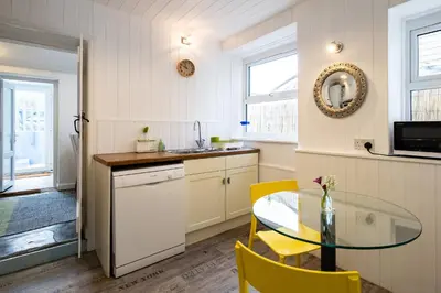 a kitchen with a glass table and yellow chairs at Seapinks in Port Isaac