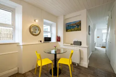 a dining room with a table and two yellow chairs at Seapinks in Port Isaac