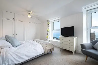 a bedroom with a bed and a tv and a chair at Seapinks in Port Isaac