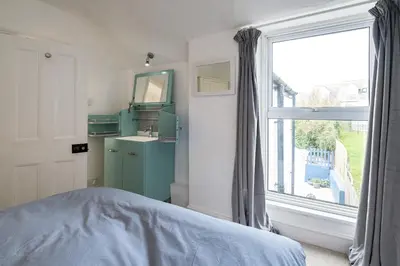 a bedroom with a bed and a sink and a window at Seapinks in Port Isaac