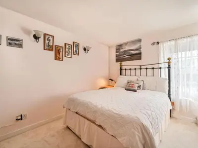 a white bedroom with a bed and a window at Holiday Home Dolphin Cottage by Interhome in Mevagissey