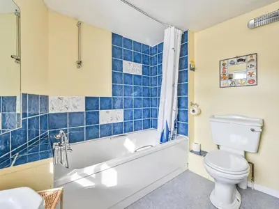 a bathroom with a tub and a toilet and a sink at Holiday Home Dolphin Cottage by Interhome in Mevagissey
