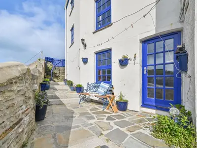 a blue door on a white building with potted plants at Holiday Home Dolphin Cottage by Interhome in Mevagissey