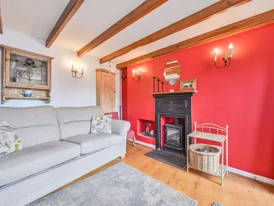 a living room with a red wall and a fireplace at Holiday Home Dolphin Cottage by Interhome in Mevagissey