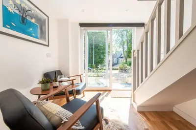 a living room with a couch and a stair case at The Studio, Rosebud. 5 minutes walk to beach. in Uny Lelant