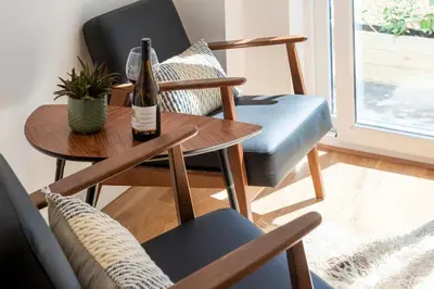 a living room with a table and a bottle of wine at The Studio, Rosebud. 5 minutes walk to beach. in Uny Lelant
