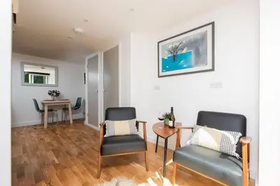 a living room with two chairs and a table at The Studio, Rosebud. 5 minutes walk to beach. in Uny Lelant