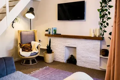 a living room with a fireplace with a tv above it at Stylish cottage in the heart of town in Lostwithiel