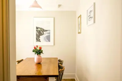 a dining room table with a vase of flowers on it at Stylish cottage in the heart of town in Lostwithiel