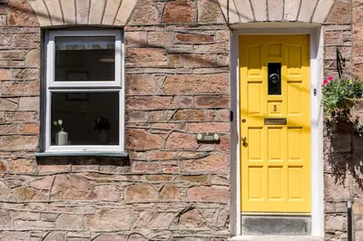 a yellow door and a window on a stone building at Stylish cottage in the heart of town in Lostwithiel