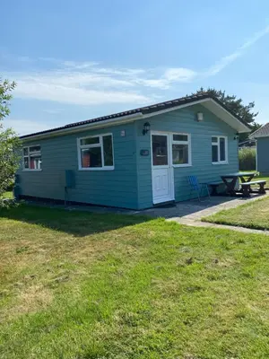 a blue house with a picnic table in the yard at Chalet 86, Atlantic Bays Holiday Park in St Merryn