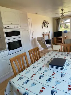 a dining room with a table with a laptop on it at Chalet 86, Atlantic Bays Holiday Park in St Merryn