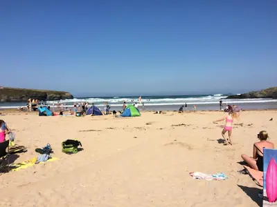 a group of people on a beach with the ocean at Chalet 86, Atlantic Bays Holiday Park in St Merryn
