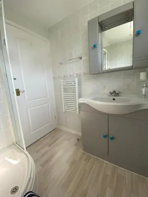 a white bathroom with a sink and a mirror at Chalet 86, Atlantic Bays Holiday Park in St Merryn