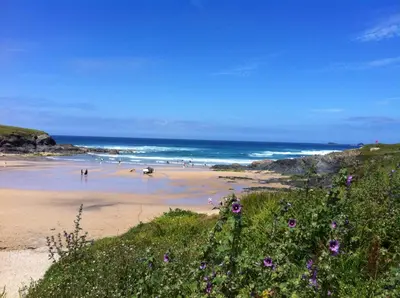 a beach with people on the sand and the ocean at Chalet 86, Atlantic Bays Holiday Park in St Merryn