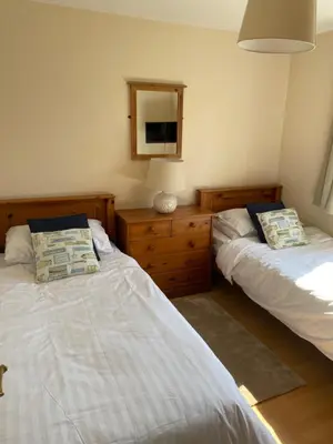 a bedroom with two beds and a dresser and a mirror at Chalet 86, Atlantic Bays Holiday Park in St Merryn