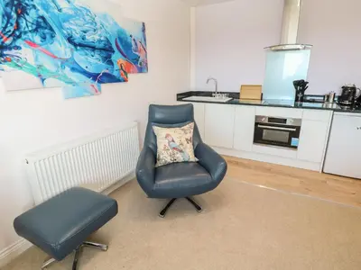 a blue chair with a pillow in a kitchen at Greenside Studio in Penzance