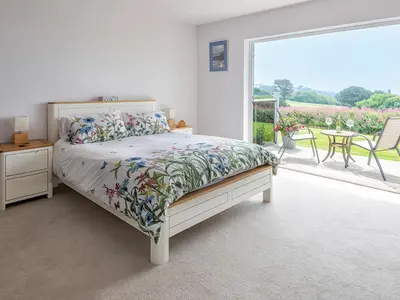 a bedroom with a bed and a balcony with a table at Greenside Studio in Penzance